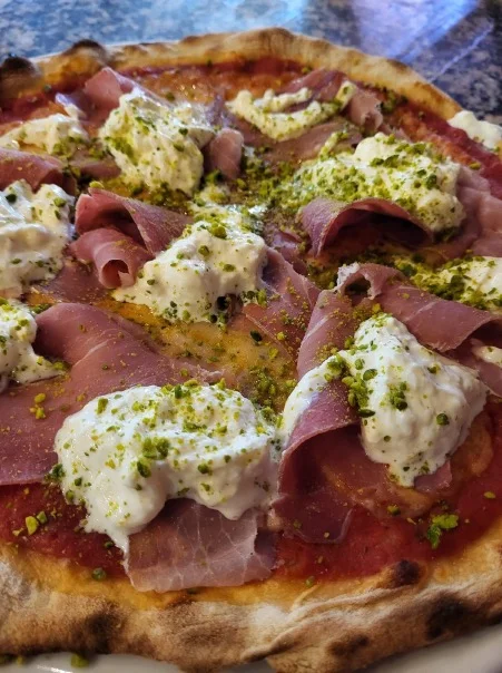 Pizza met speck, kaas en pistache uit de oven