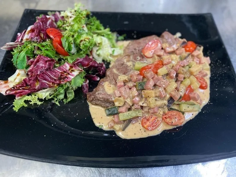 Visfilet met gestoofde tomaat en gemengde salade op een donker bord